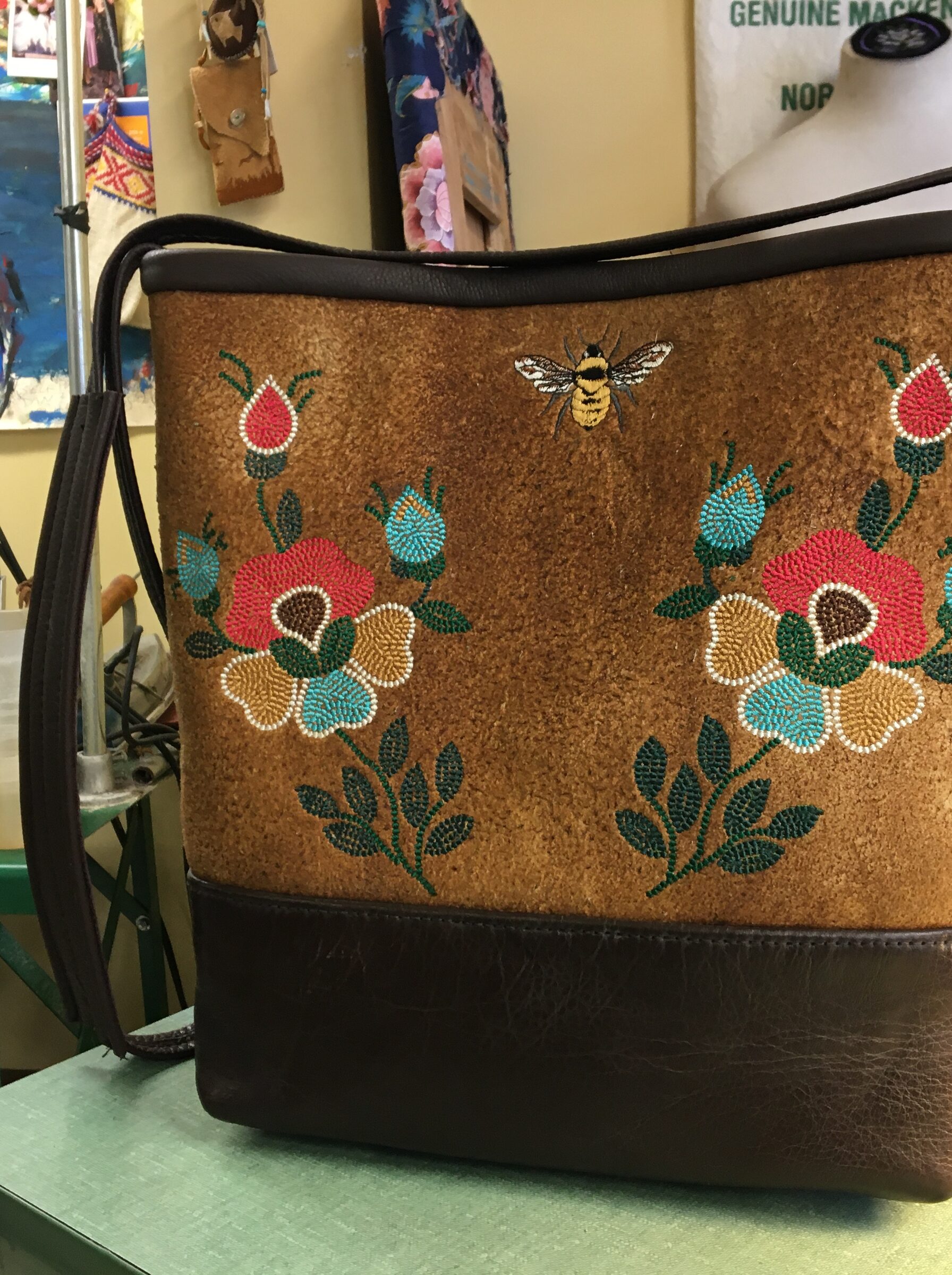 Tan hide tote with two beaded roses, a bee, black leather base and strap