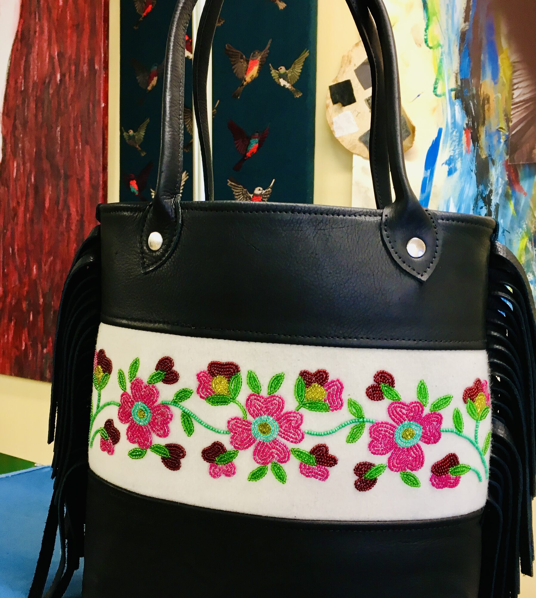 Black leather tote with a white band of beaded roses and black hide fringe.