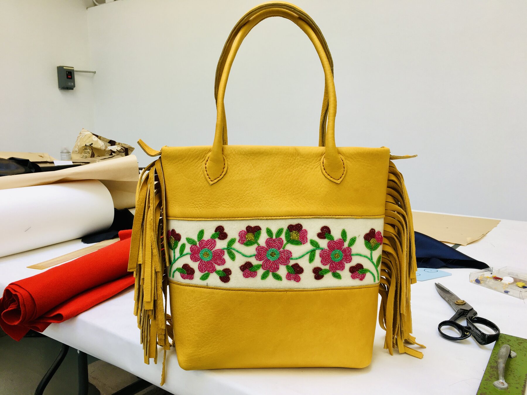 Tan leather tote with floral beadwork and fringe.