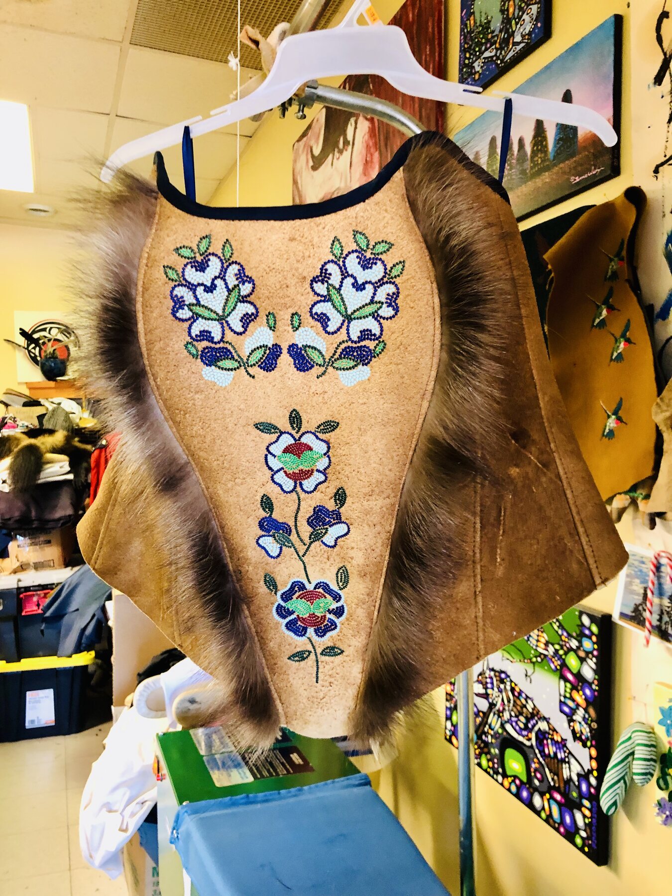 Beaded hide poncho with fox trim and floral panels.