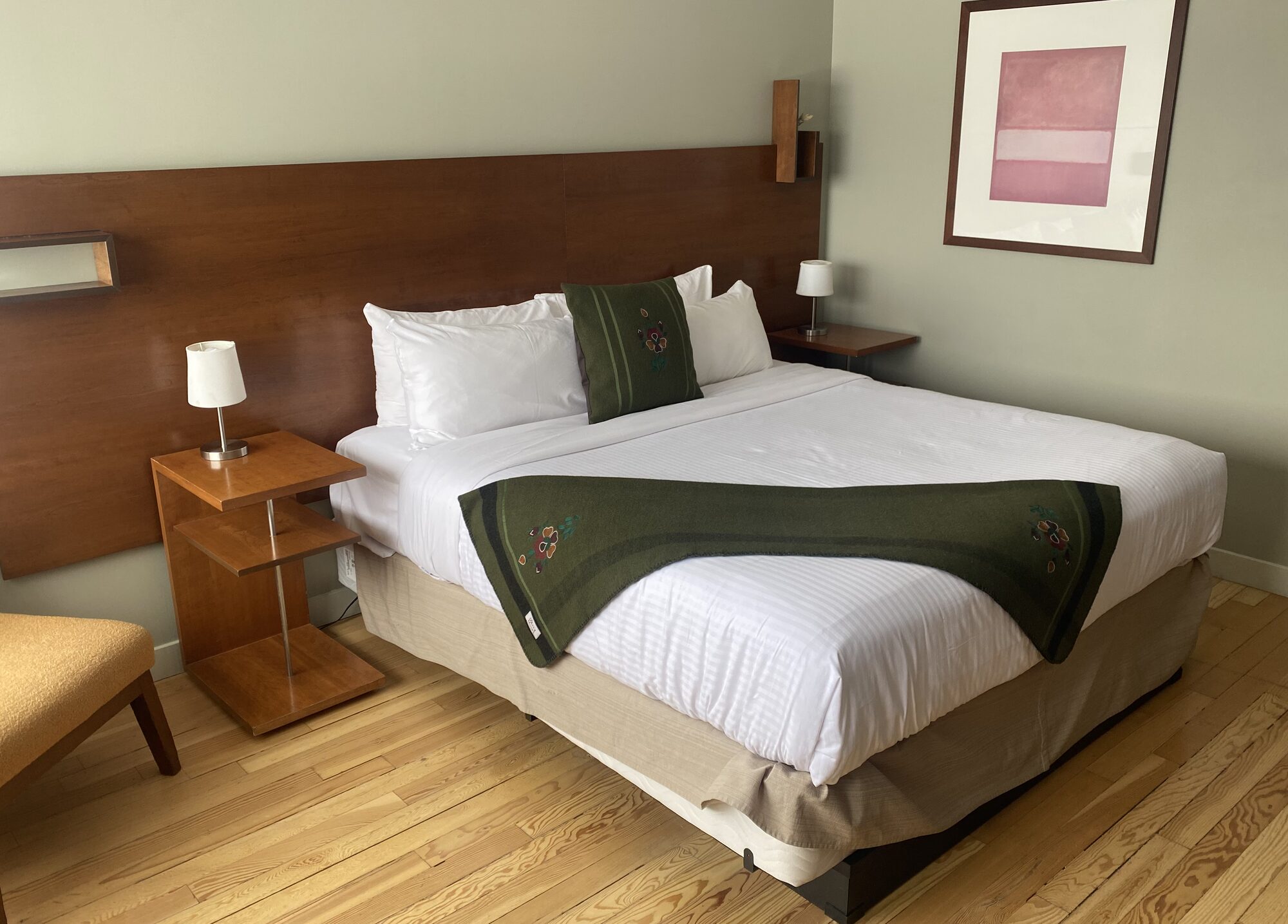 Olive embroidered pillow and runner on a bed