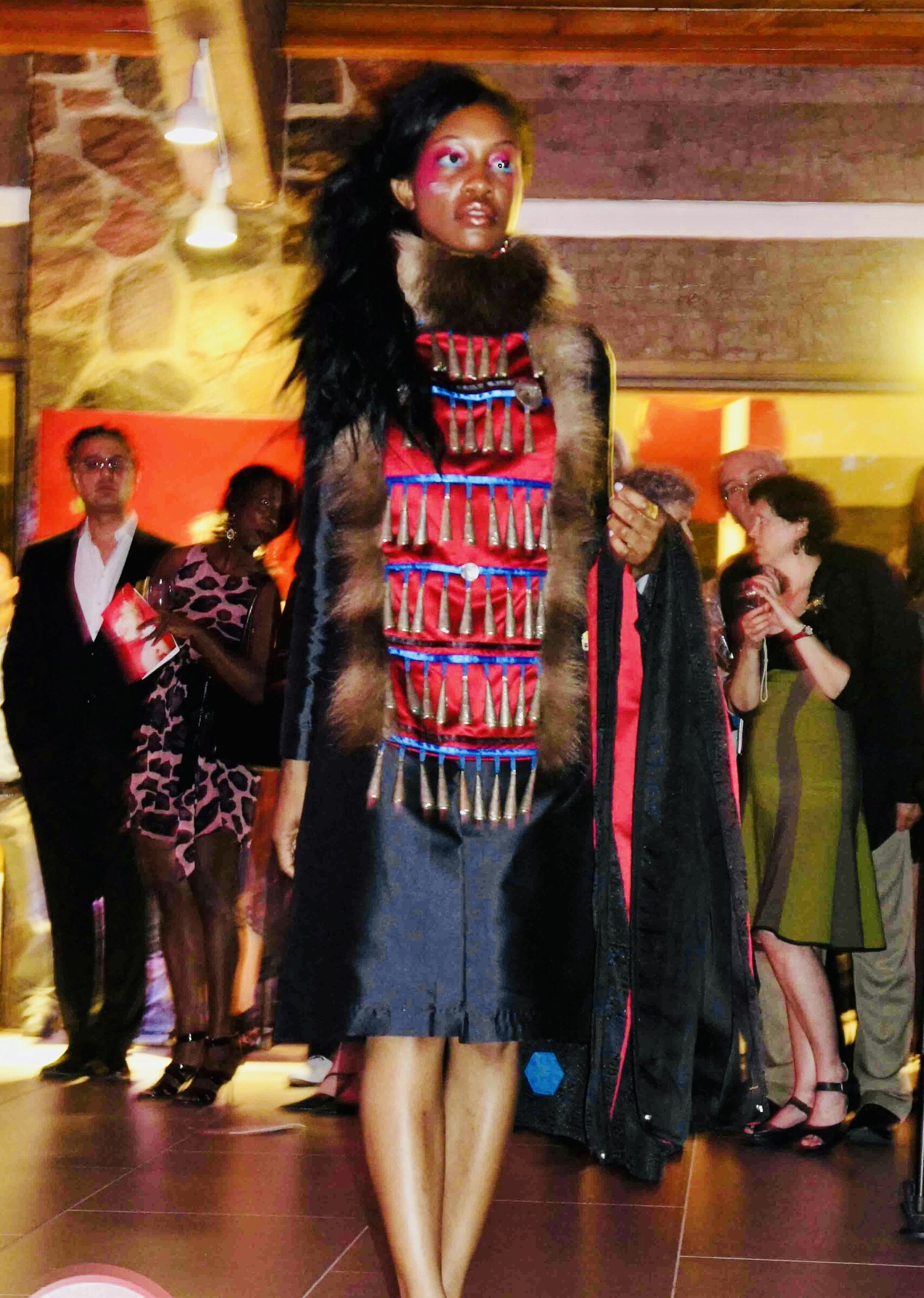 Runway look with a red panel, fur collar, and hanging jingles