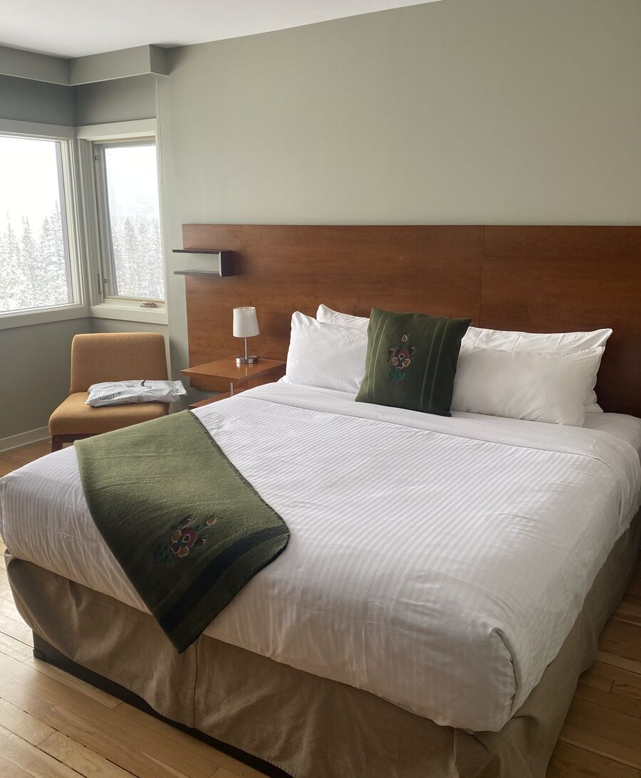 Olive embroidered pillow and throw on a bed, snow outside