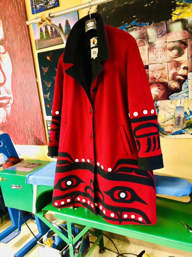 Red and black formline coat on a studio table